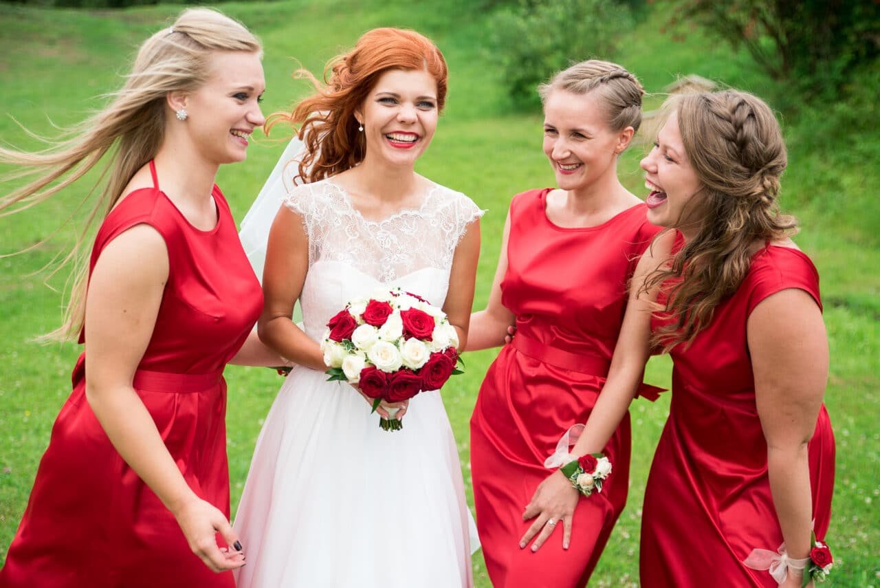 Kāzu foto ar līgavu un līgavas māsām sarkanās kleitās